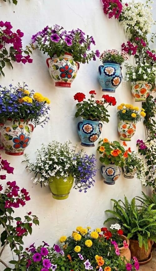 Macetas de cerámica artesanal coloridas con flores en bloom en pared blanca de Marbella Views, Ojén