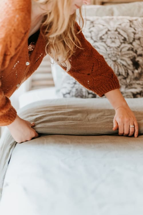 Woman arranging bedding at Gites du Bulz, a cozy bed and breakfast in Pleyber-Christ, France