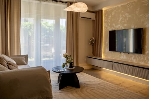 Modern Japandi suite at Le 1 Péraudel in Castres with beige sofa, flat-screen TV, and garden view through large windows