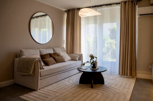 Modern Japandi living room suite at Le 1 Péraudel with beige sofa, black coffee table, round mirror and garden view in