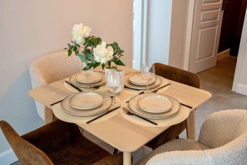 Elegant dining setup at Le 1 Péraudel with place settings, white flowers, and modern chairs in a garden-view suite.