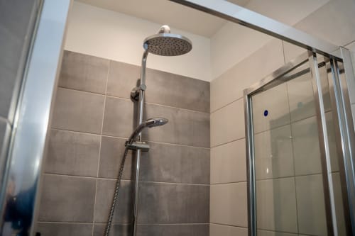 Modern shower with rainfall head and hand spray in Le 1 Péraudel Suite's Japandi-style bathroom, Castres