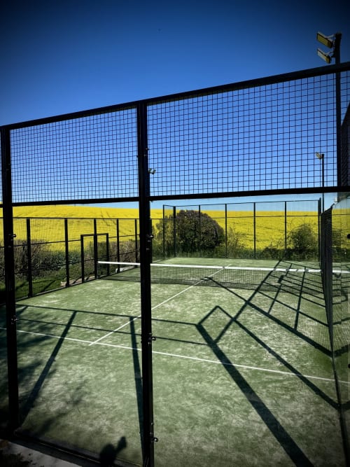 Courts de padel de l'hôtel hellofamily à Chaville avec champ de colza jaune en arrière-plan
