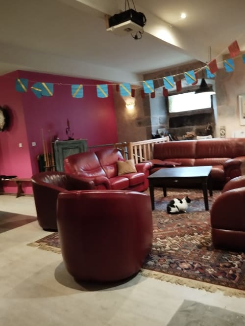 Sièges en cuir bordeaux et guirlandes colorées dans la chaleureuse salle commune du Domaine De Maleval, Mars FR