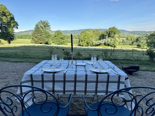 Table de salle à manger extérieure avec nappe à carreaux bleus surplombant la campagne du Morvan au Château de Vaux