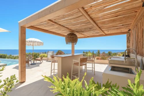 Luxury Mediterranean terrace at Jc Conciergerie with wooden pergola, bar seating, and sea views in Bandol, France