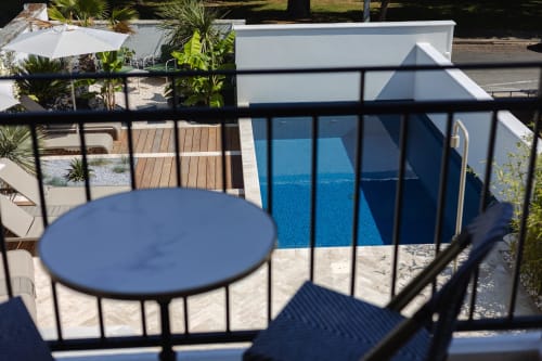 Vue sur la piscine depuis la terrasse du gîte L'Ode à Pierre à Dax, France avec parasol bleu