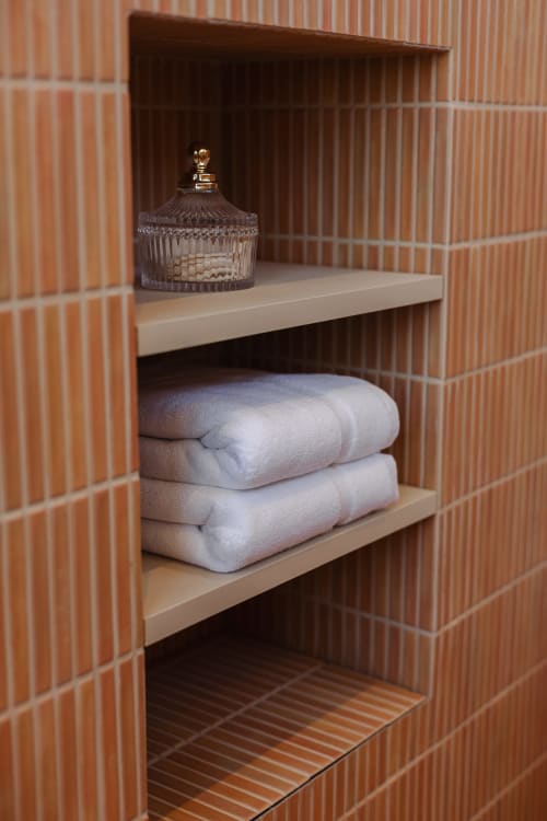 Étagères intégrées de salle de bain avec serviettes blanches pliées et vase décoratif en verre à L'Ode à Pierre, Dax