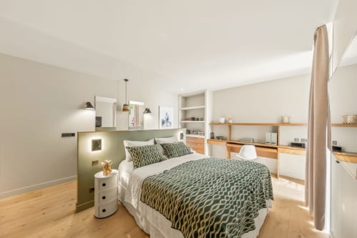 Modern villa bedroom in Bandol with queen bed, green patterned bedding, wooden storage, and sea view at Jc Conciergerie