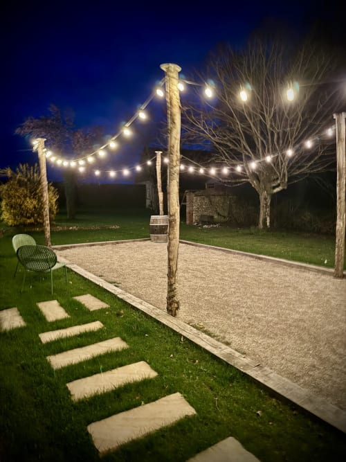 Terrain de pétanque illuminé de l'hôtel hellofamily à Chaville avec guirlandes lumineuses et surface en gravier au crépuscule