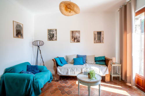 Séjour lumineux avec fauteuil turquoise, canapé beige, table ronde et vue sur jardin au Le Mas De La Clé D'Or