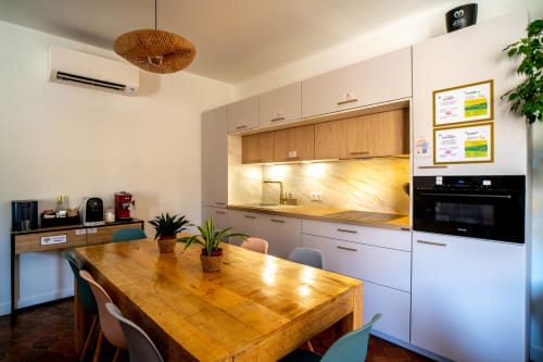 Cuisine contemporaine avec table à manger en bois, électroménagers blancs et éclairage ambiant de la suite luxe Le Mas De La Clé D'Or.