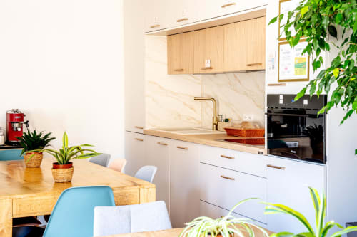 Cuisine moderne avec placards en bois et crédence marbre, coin repas avec plantes au Mas De La Clé D'Or