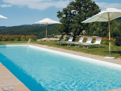 Piscina di Lodole Country House con lettini, ombrelloni e vista sui monti Monzuno in Italia