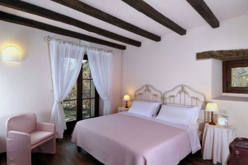 Camera Sunrise Superior presso la Lodole Country House B&B a Monzuno con biancheria rosa, travi a vista e vista sul giardino