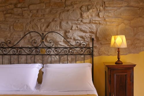 Camera Sun Superior presso Lodole Country House a Monzuno, con elegante letto in ferro battuto, cuscini bianchi e muri in pietra