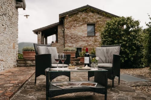 Zona soggiorno esterna presso Lodole Country House a Monzuno con vino e fiori con vista sul giardino e sulla storica villa in pietra