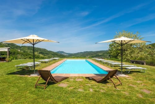 Area piscina di Lodole Country House con sdraio, ombrelloni e vista sulla campagna italiana a Monzuno