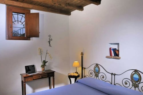 Camera Sky presso Lodole Country House a Monzuno con letto blu, scrivania in legno e testata in ferro battuto ornamentale