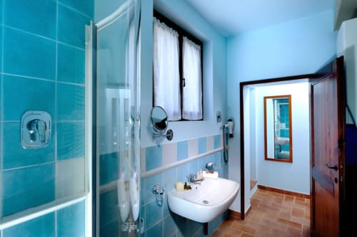 Bagno moderno con piastrelle turchesi, lavabo bianco e cabina doccia a Lodole Country House, Monzuno