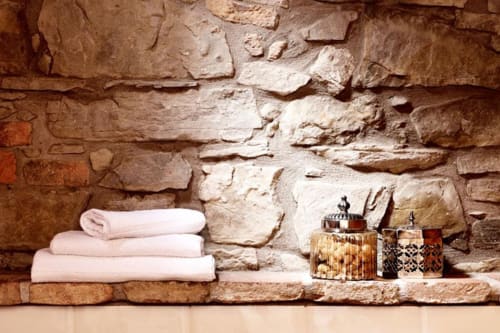 Rustica mensola in pietra a Lodole Country House con asciugamani rosa piegati e vasi decorativi ambra