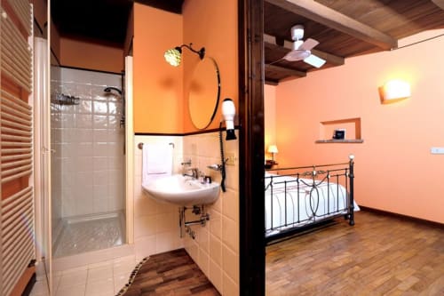 Camera Tramonto di Lodole Country House con pareti arancioni, bagno en-suite, doccia, lavabo, letto con testata in metallo e arredo in legno
