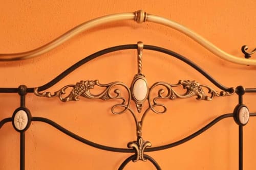 Elegante testata letto in ottone con decorazioni a volute presso Lodole Country House a Monzuno