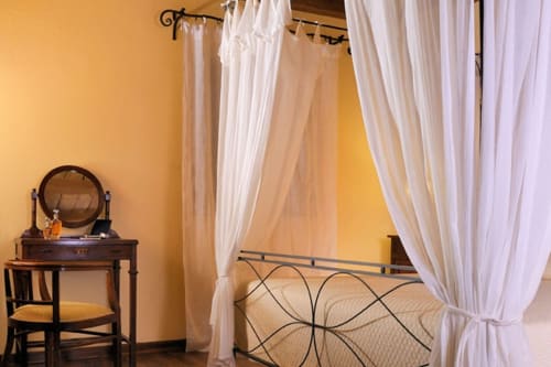 Elegante camera da letto a Lodole Country House con letto a baldacchino, tende bianche e scrivania a Monzuno
