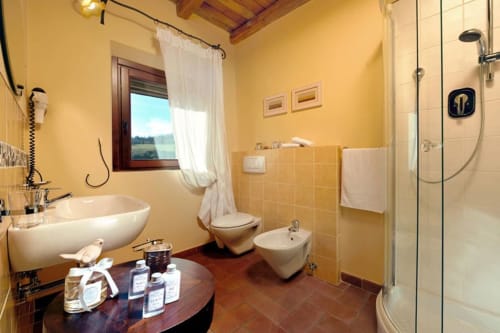 Bagno luminoso nella Lodole Country House di Monzuno con pareti gialle, doccia moderna, toilet, bidet e eleganti rubinetterie