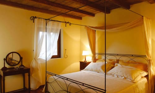 Camera da letto giallo brillante a Lodole Country House a Monzuno, Italia, con letto a baldacchino e tende trasparenti