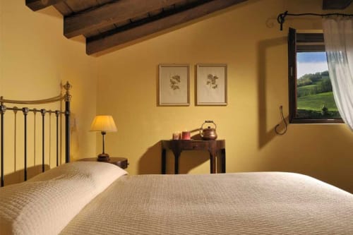 Camera da letto calda e accogliente presso la Lodole Country House con letti gemelli, travi in legno e vista sulla campagna