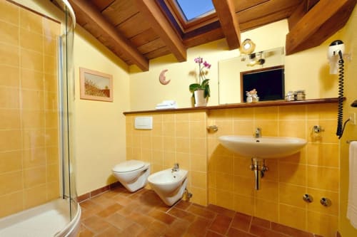 Bagno luminoso con piastrelle gialle, wc, bidet, lavabo, specchio e doccia nella camera Luna, Lodole Country House, Monzuno