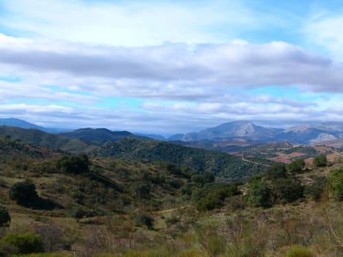 Vista panorâmica do vale montanhoso do Hotel Balcón De Los Montés em Colmenar, Espanha, com colinas ondulantes e céu azul