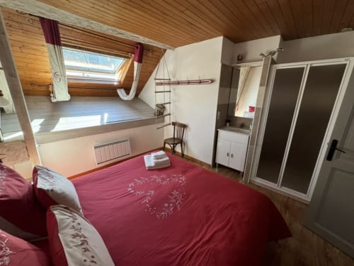 Chambre douillette à La Jument Verte avec literie rouge, plafond en bois et lucarnes