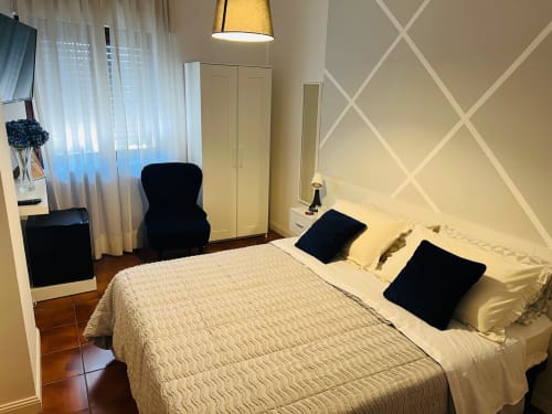 Camera moderna presso Aniene Home Roma B&B con letto color crema, cuscini neri, motivi geometrici alle pareti e zona di lavoro a Roma