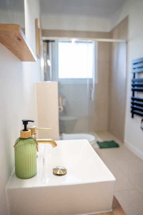 Lavabo moderne avec distributeur de savon vert et robinetterie en laiton dans la Suite du Pacte Secret au gîte de luxe Le Mas De La Clé D'Or