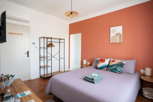 Suite chambre moderne au Mas De La Clé D'Or avec literie lavande, mur accent terre cuite et vue sur le jardin