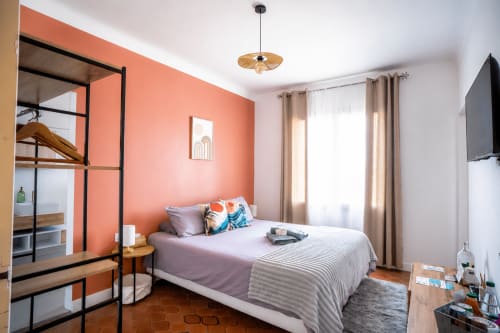 Chambre lumineuse au Mas De La Clé D'Or avec mur accent corail, lit queen, vue sur jardin et équipements modernes