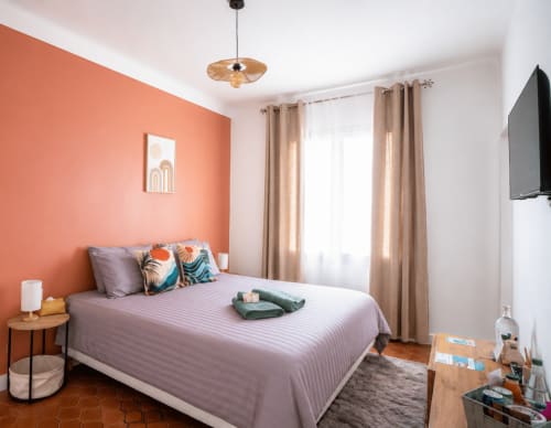 Chambre moderne avec mur accent corail, literie violette et vue sur le jardin au Mas De La Clé D'Or à Puget sur Argens