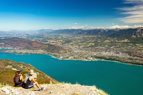 Des randonneurs admirent le lac Annecy turquoise depuis un belvédère montagneux à Trévignin, Alpes françaises