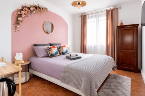 Suite luxueuse au Mas De La Clé D'Or avec mur d'accent rose, literie violette et mobilier en bois à Puget sur