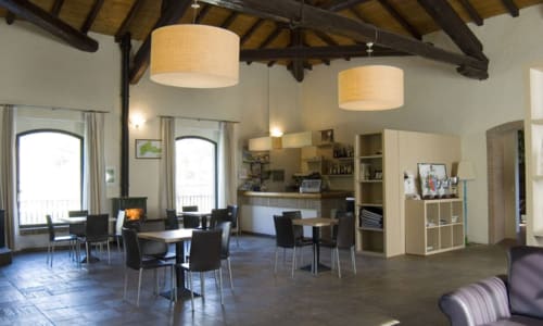 Ampio salotto open-plan presso la Lodole Country House a Monzuno, Italia, con travi in legno, lampadari a sospensione e tavoli da pranzo