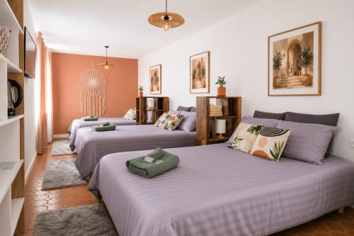 Suite luxe 6 personnes au Mas De La Clé D'Or avec lits jumeaux, parure violette, mur d'accent orange et tableaux encadrés