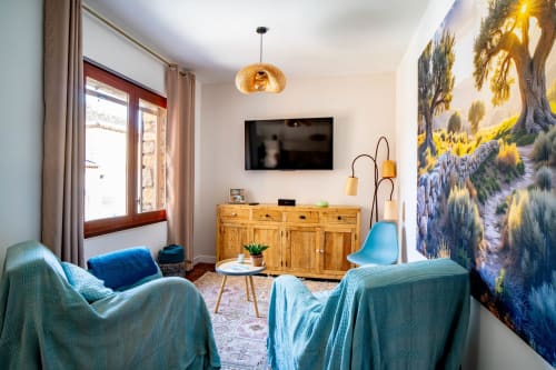 Élégant salon du Mas De La Clé D'Or avec fauteuils bleus, meuble en bois et grande fresque nature