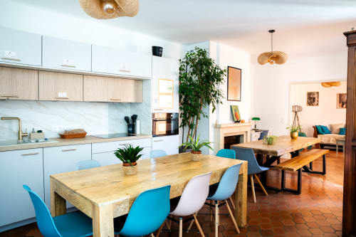 Cuisine-salle à manger moderne au Mas de la Clé d'Or avec meubles blancs, tables en bois, chaises bleues et verdure