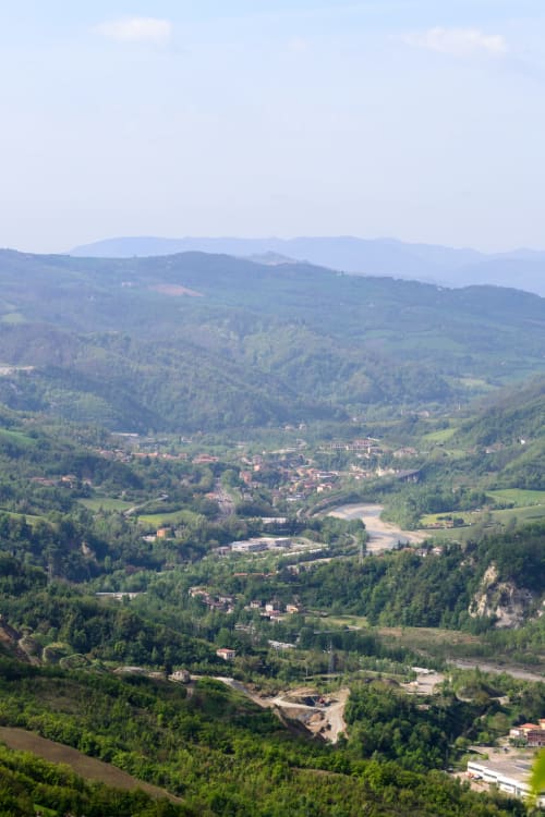 Vista aerea della valle di Monzuno con boschi verdi, fiume e sparse abitazioni nella campagna italiana
