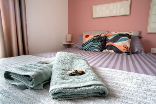 Chambre luxueuse du Mas De La Clé D'Or avec serviettes pliées, lit rayé et murs rose à Puget sur Argens