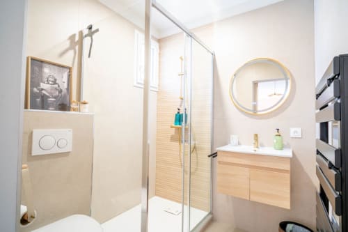 Salle de bain moderne avec douche vitrée, meuble vasque en bois et miroir rond au Mas De La Clé D'Or, luxueux B&B à Puget sur Argens