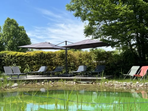 Espace détente au bord de l'eau à La Jument Verte avec parasols et chaises longues