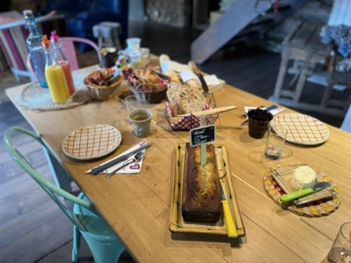 Table du petit-déjeuner à La Jument Verte avec viennoiseries, pain, jus d'orange et couverts en Provence.